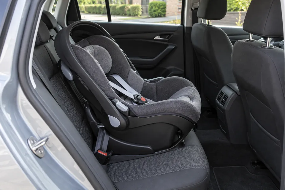 Siège enfant vide avec harnais sur la banquette arrière d’une voiture stationnée.