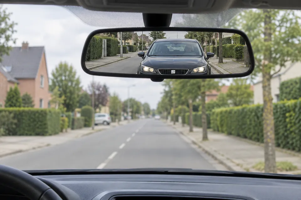 Voiture sombre visible derrière le véhicule dans le rétroviseur intérieur.