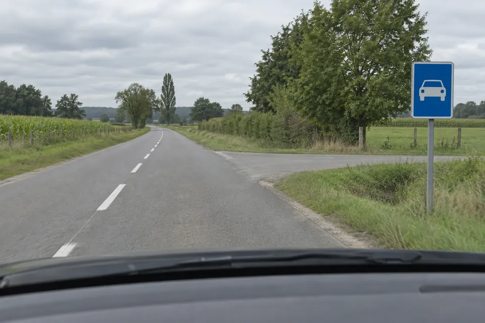 Une route latérale rejoint une chaussée signalée comme route pour automobiles.