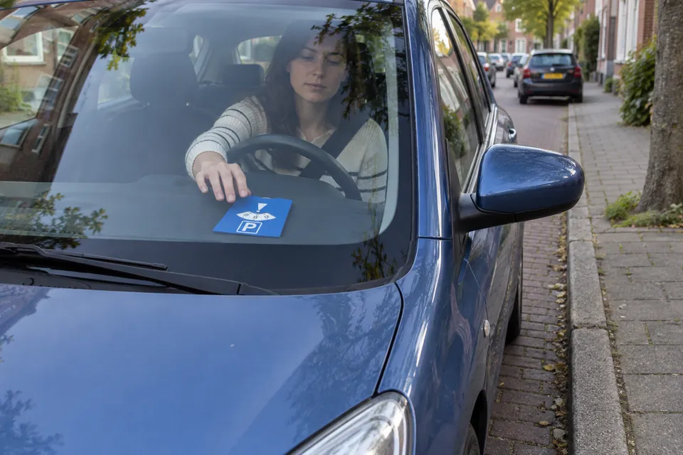 Une conductrice approche sa main du disque posé sur le tableau de bord.