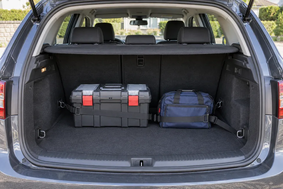 Coffre ouvert contenant une caisse à outils et un sac avec des sangles devant les dossiers arrière.