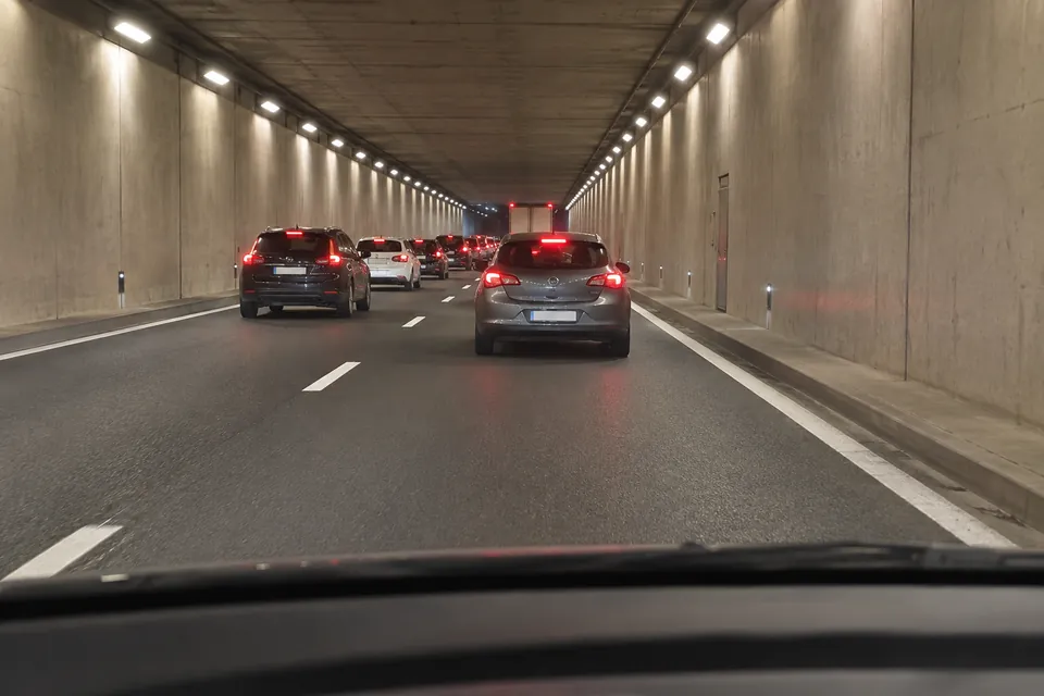 File de voitures aux feux de freinage allumés dans un tunnel, avec un espace devant le véhicule observateur.